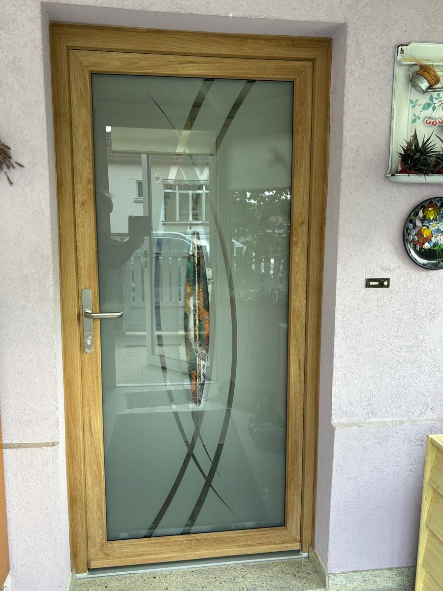Porte d’entrée PVC Aluplast décor chêne avec vitrage sablé décoratif, posée par Fenêtres Jung dans le Bas-Rhin